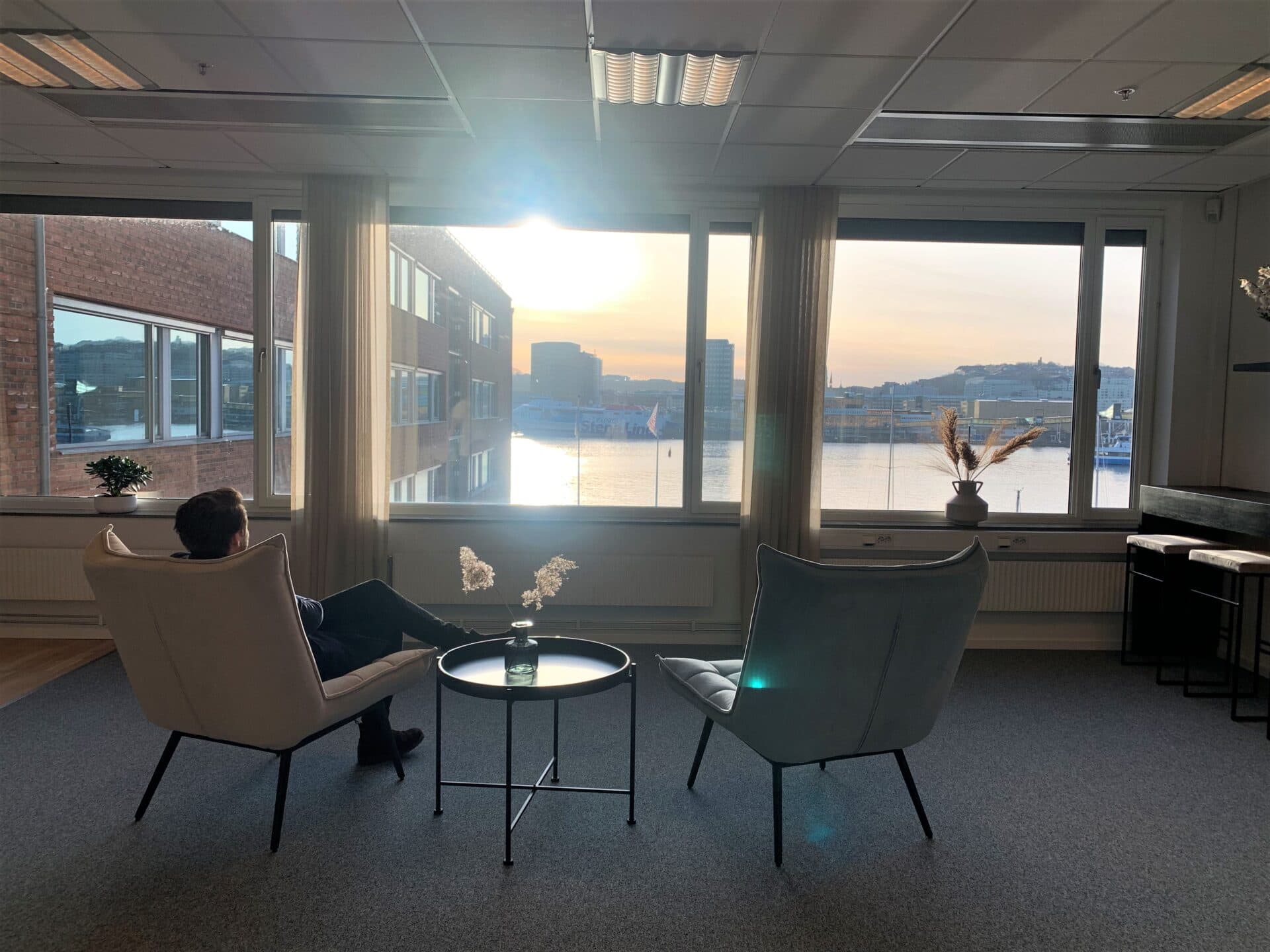 Fåtöljer vid fönstret med utsikt över hamnen och färjan